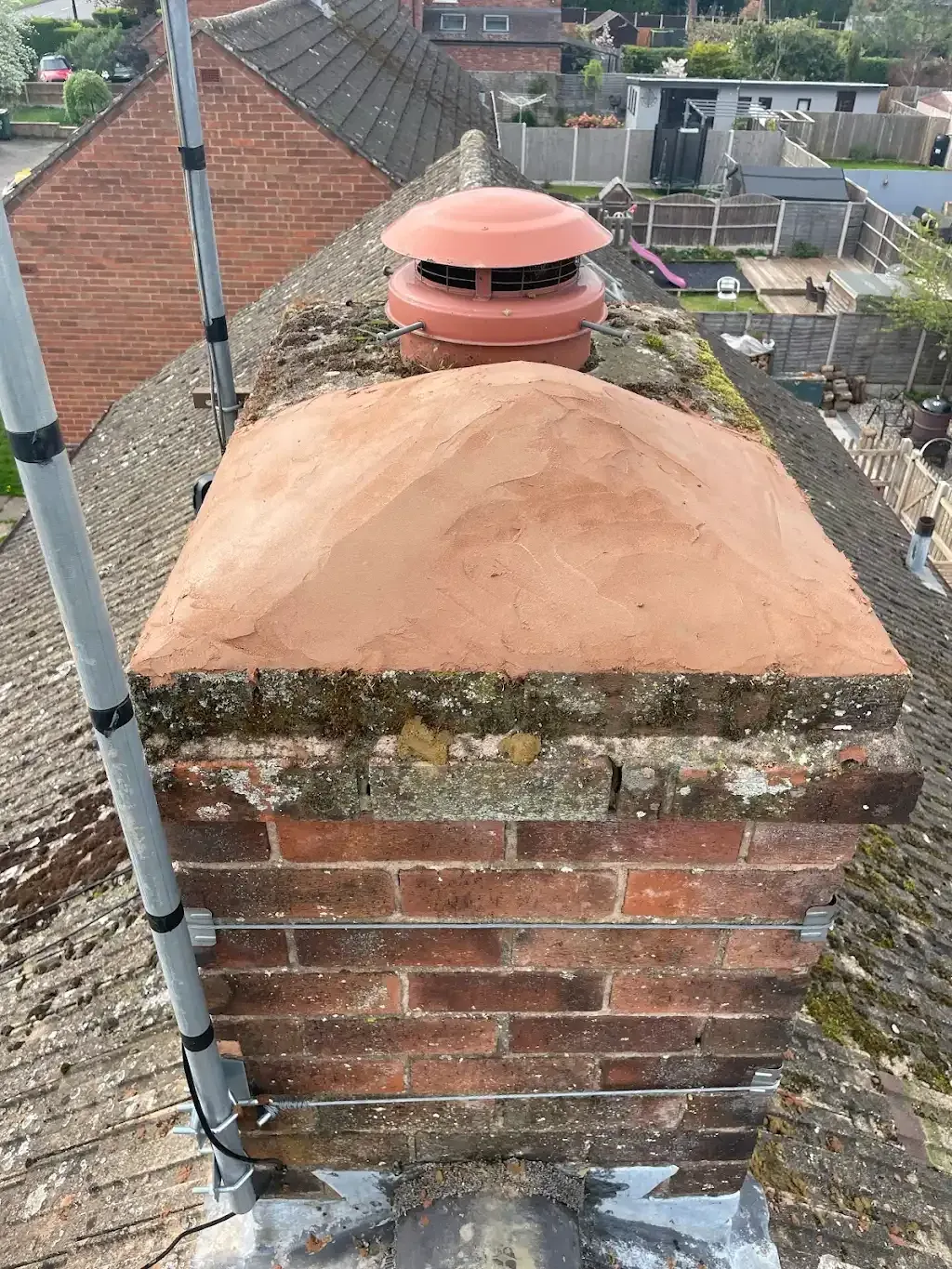 Repointed chimney stack with fresh mortar crown and terracotta cowl